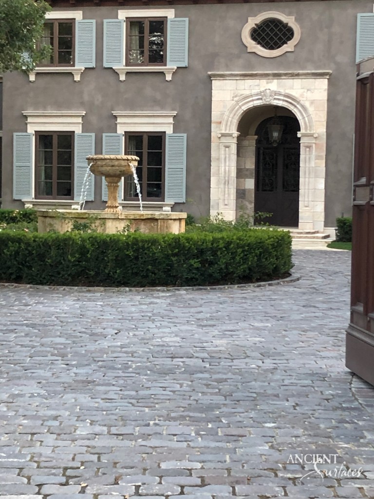 Stunning limestone villa entrance featuring an Antique Reclaimed Italian Limestone Portal, Ancient Roman Basalt Cobblestone Driveway  and a very unique Reclaimed Limestone Fountain all supplied and executed by Ancient Surfaces.