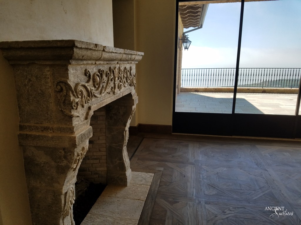 A cozy living room centered around a limestone fireplace with intricate carvings, where every flame seems to narrate tales of yesteryears