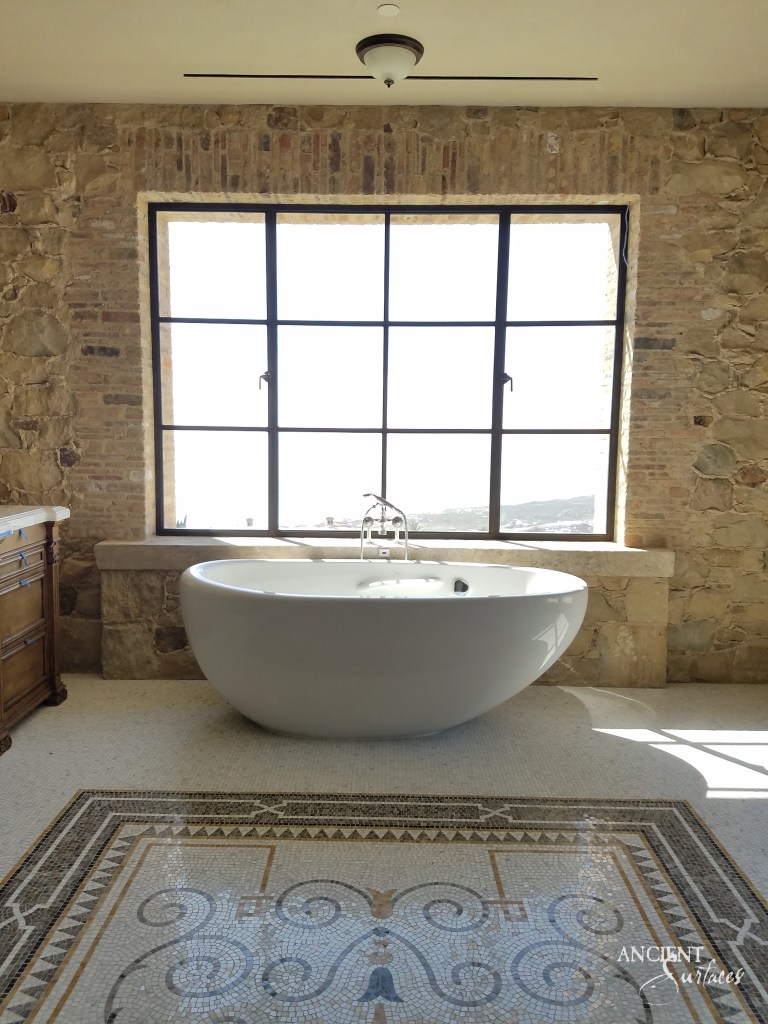 An opulent bathroom showcasing walls adorned with limestone cladding and mosaics floor embodying the artistry of Ancient Surfaces
